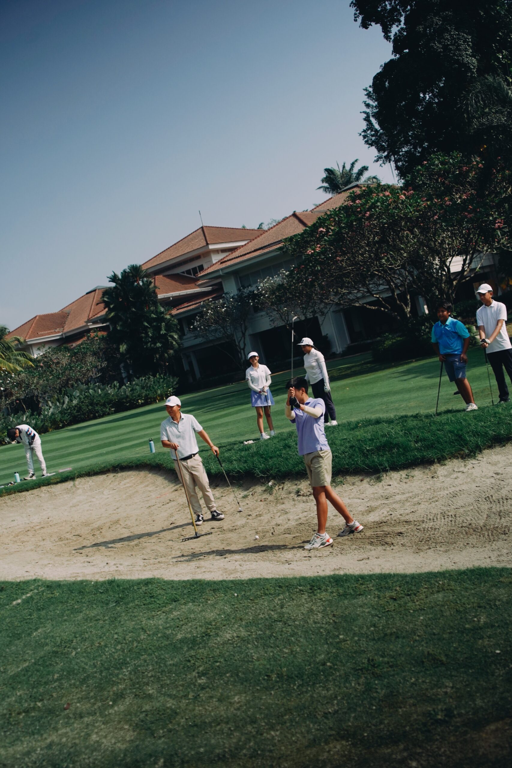 Practicing golf swing at the bunker with coach